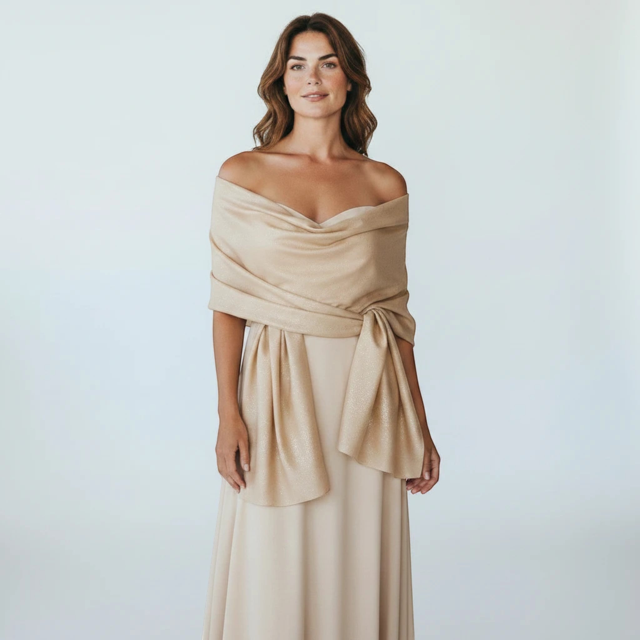 MiRA beige sjal i polyester med subtila glitterdetaljer, draperad över axlarna på en kvinna i festklänning.