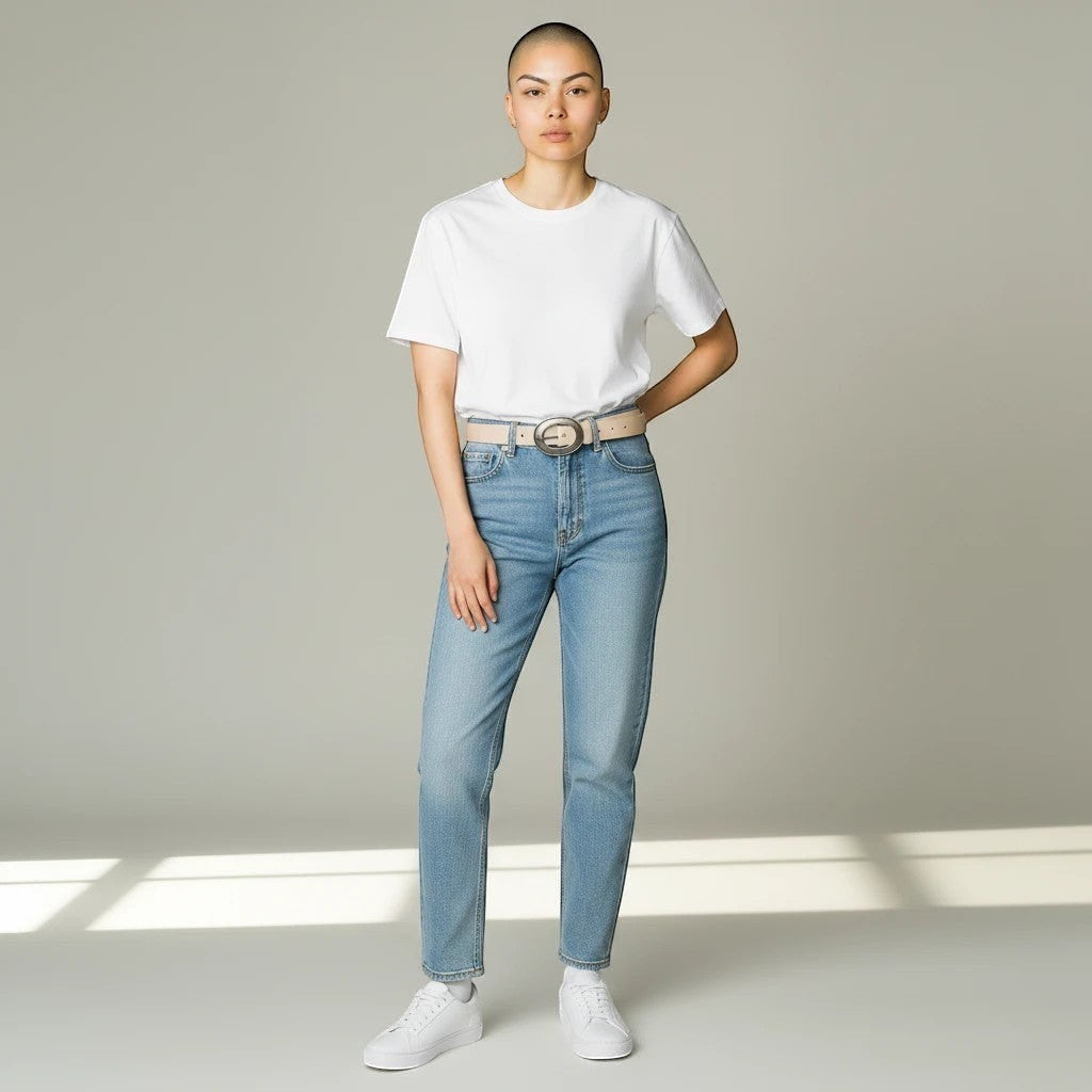MiRA beige skärp i veganskt läder med silverfärgat spänne buret av en korthårig modell i vit t-shirt och jeans.