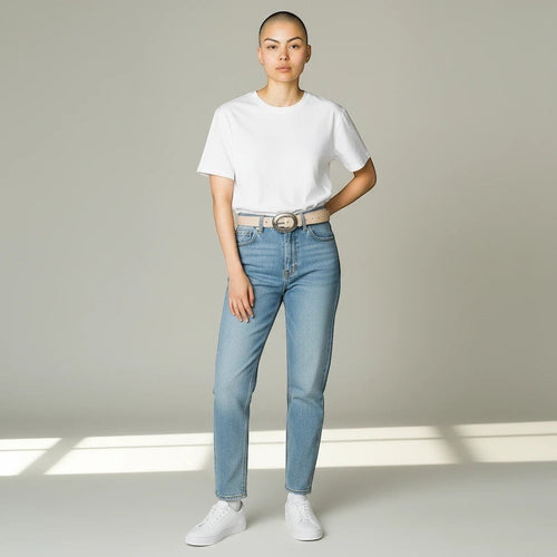 MiRA beige skärp i veganskt läder med silverfärgat spänne buret av en korthårig modell i vit t-shirt och jeans.