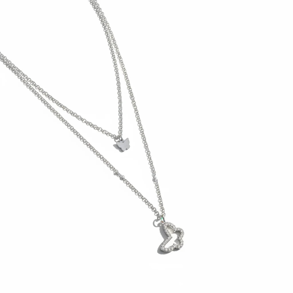 MiRA dubbelt halsband i silvertonad metall med en slät fjäril och en större fjäril prydd med gnistrande stenar.