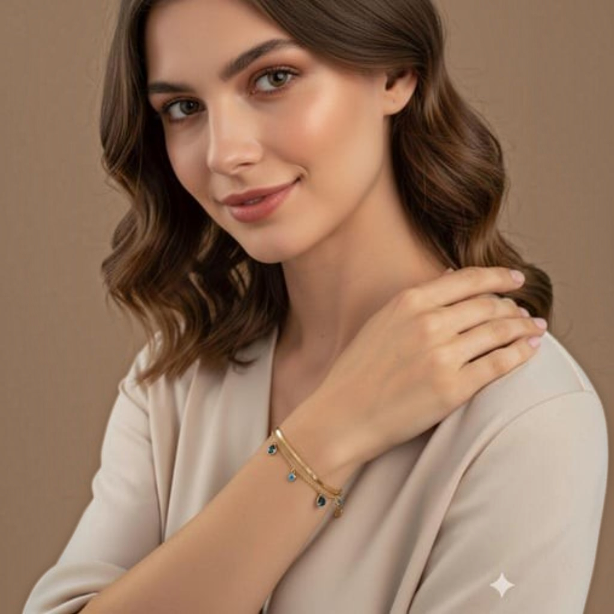 MiRA guldpläterat armband i 316L stål med blå evil eye-detaljer på en kvinna i beige topp.