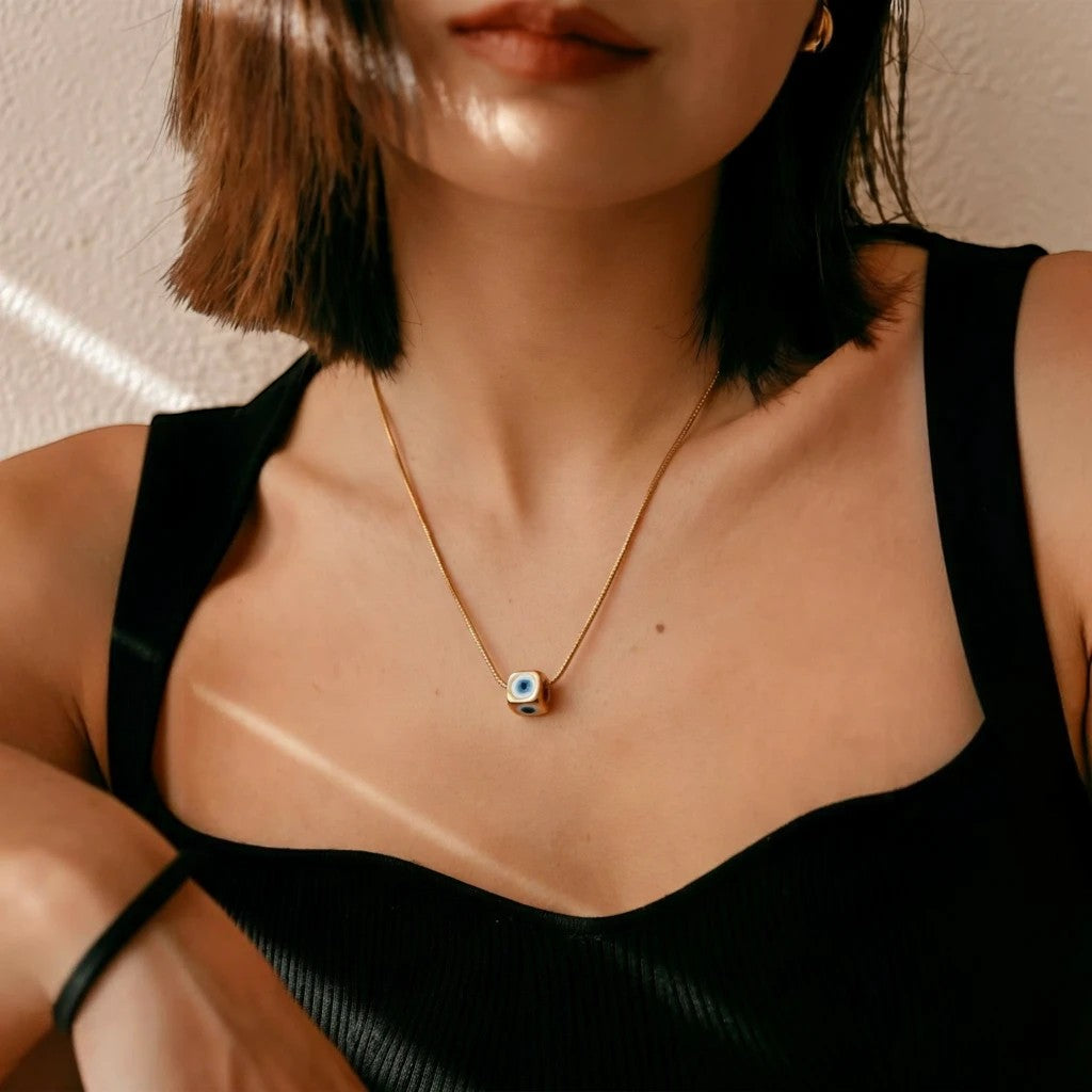 MiRA guldhalsband i rostfritt stål med en fyrkantig nazar boncugu evil eye-berlock på en kvinna