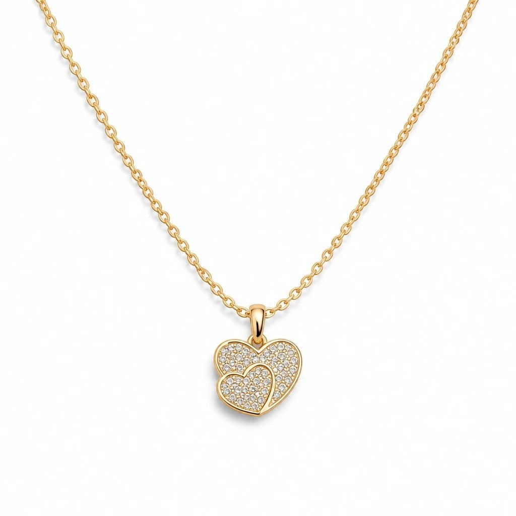 MiRA halsband i guld med ett hjärtformat hänge prytt med gnistrande stenar och en tunn kedja.