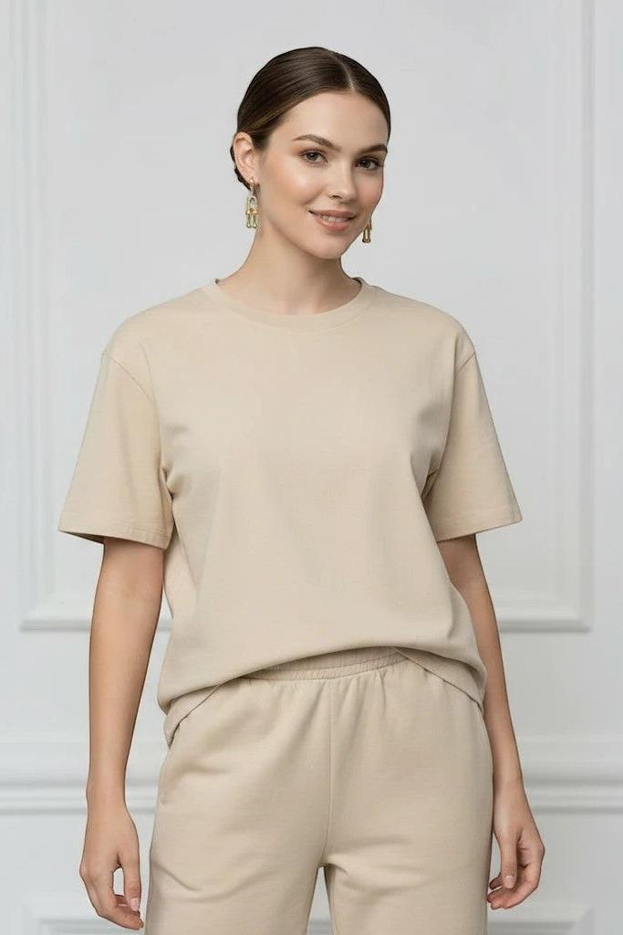 MiRA guldiga örhängen i rostfritt stål burna av en kvinna i beige t-shirt och matchande byxor