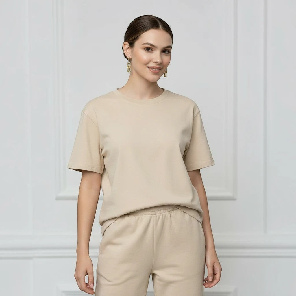 MiRA guldiga örhängen i rostfritt stål burna av en kvinna i beige t-shirt och matchande byxor