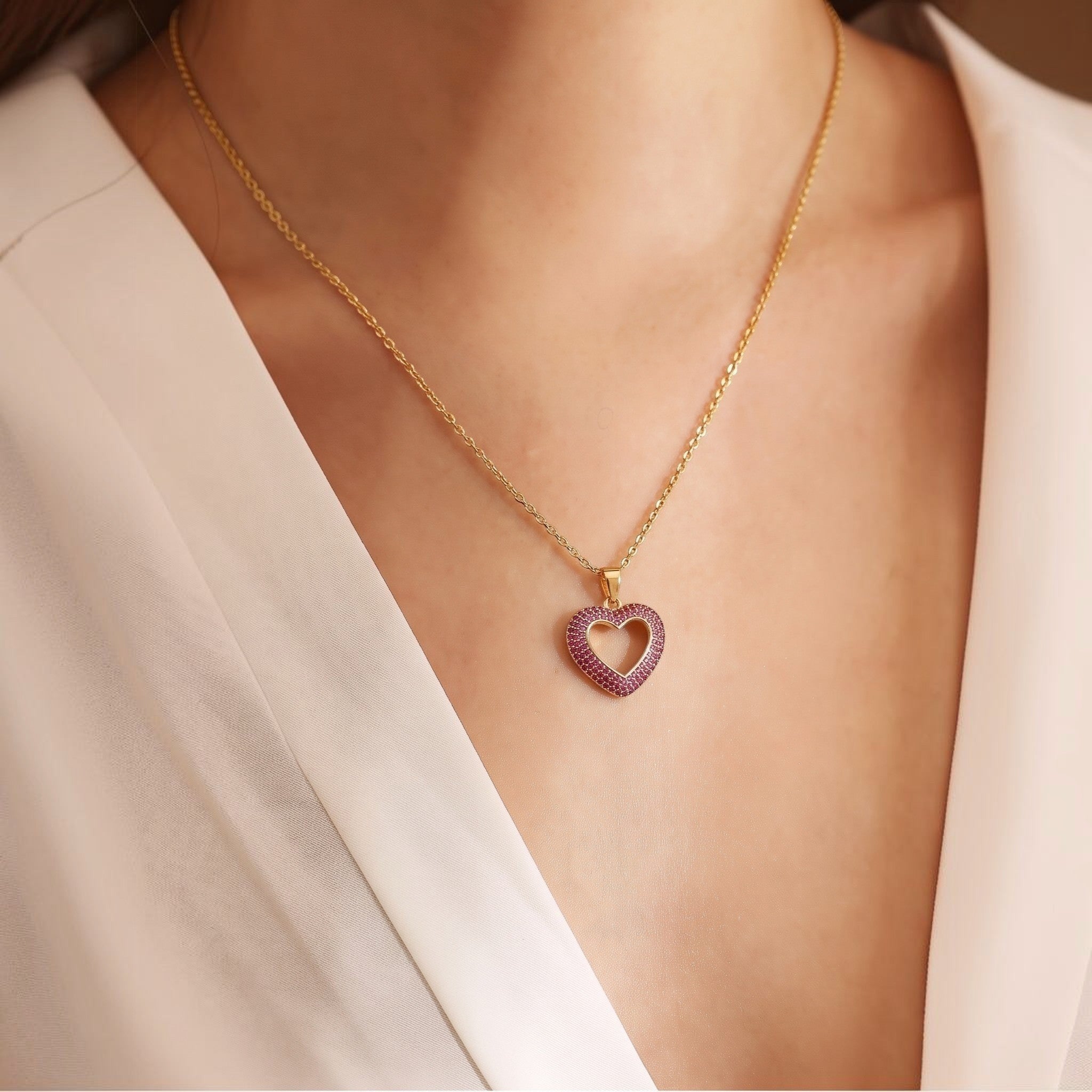 MiRA halsband i guldpläterat rostfritt stål med hjärtformat hänge prytt med små rosa stenar på en modell