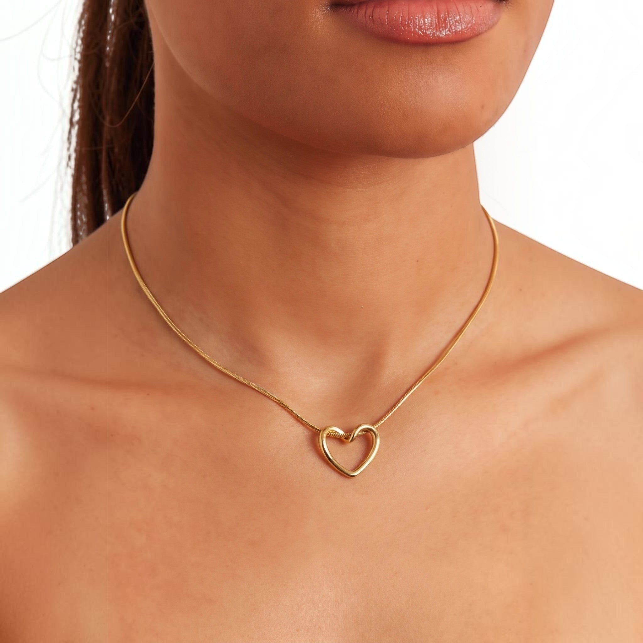 MiRA halsband i guldpläterat rostfritt stål med ett elegant hjärtformat hänge på en kvinna