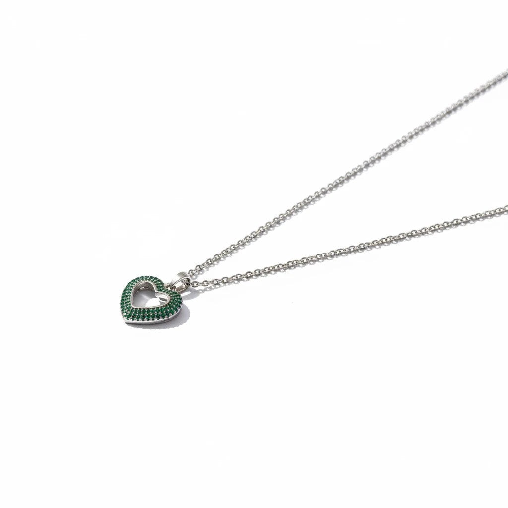 MiRA halsband i rostfritt stål med hjärtformat hänge prytt av små gröna stenar och en elegant silverfärgad kedja.