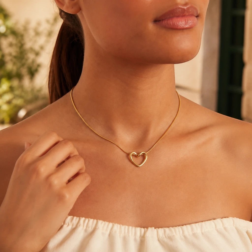 MiRA justerbart halsband i guldfärgat rostfritt stål 316L med ett elegant hjärtformat hänge på en kvinna.