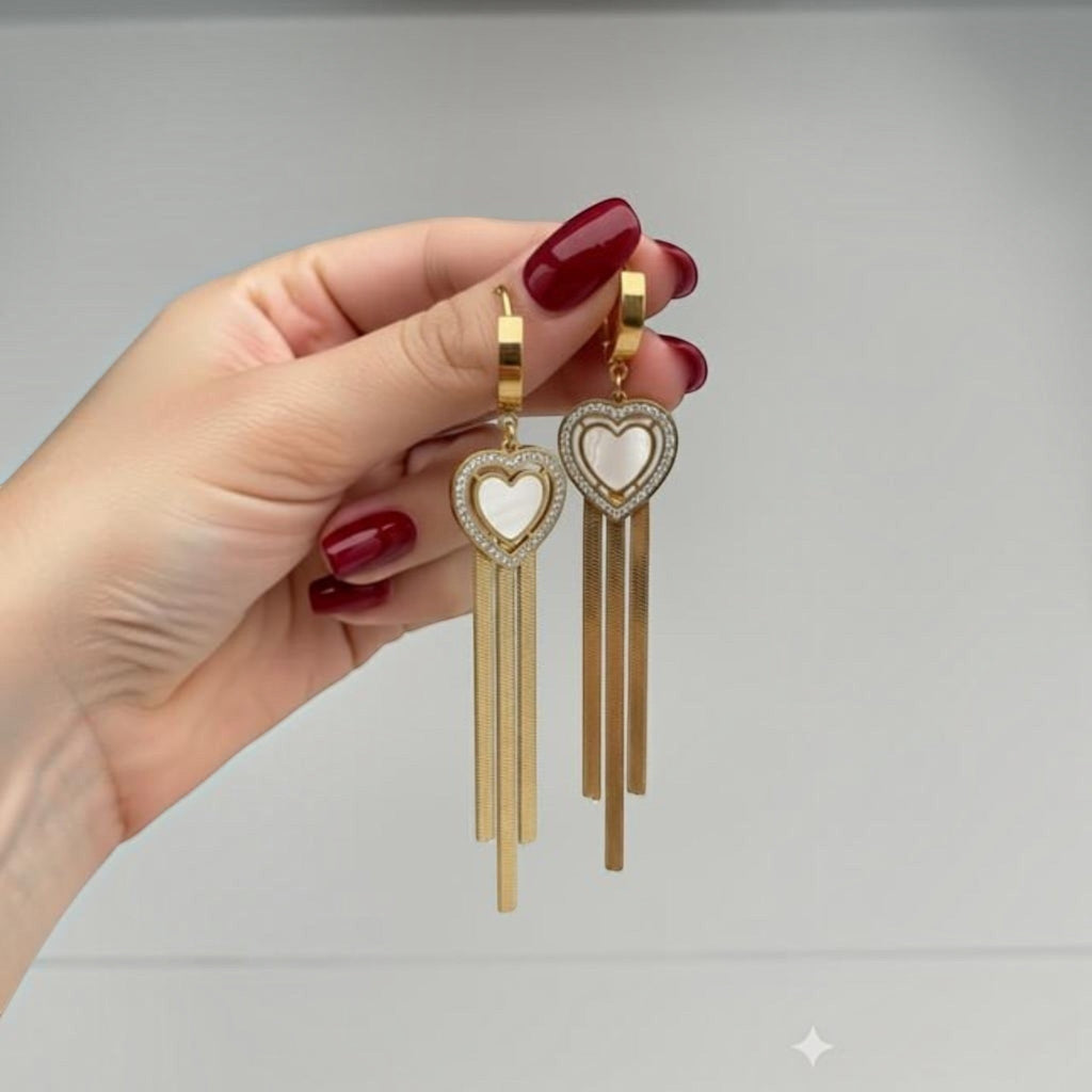 MiRA hjärtformade hängande örhängen i guld med pärlemor, gnistrande stenar och eleganta kedjehängen.