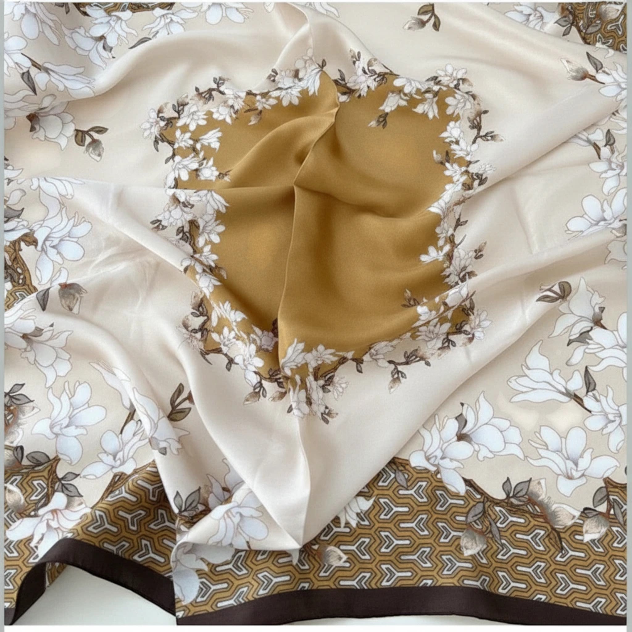 MiRA kvadratisk sjal med blommigt mönster i beige, guld och mörkbrunt med en mjuk lyster och geometriska detaljer.