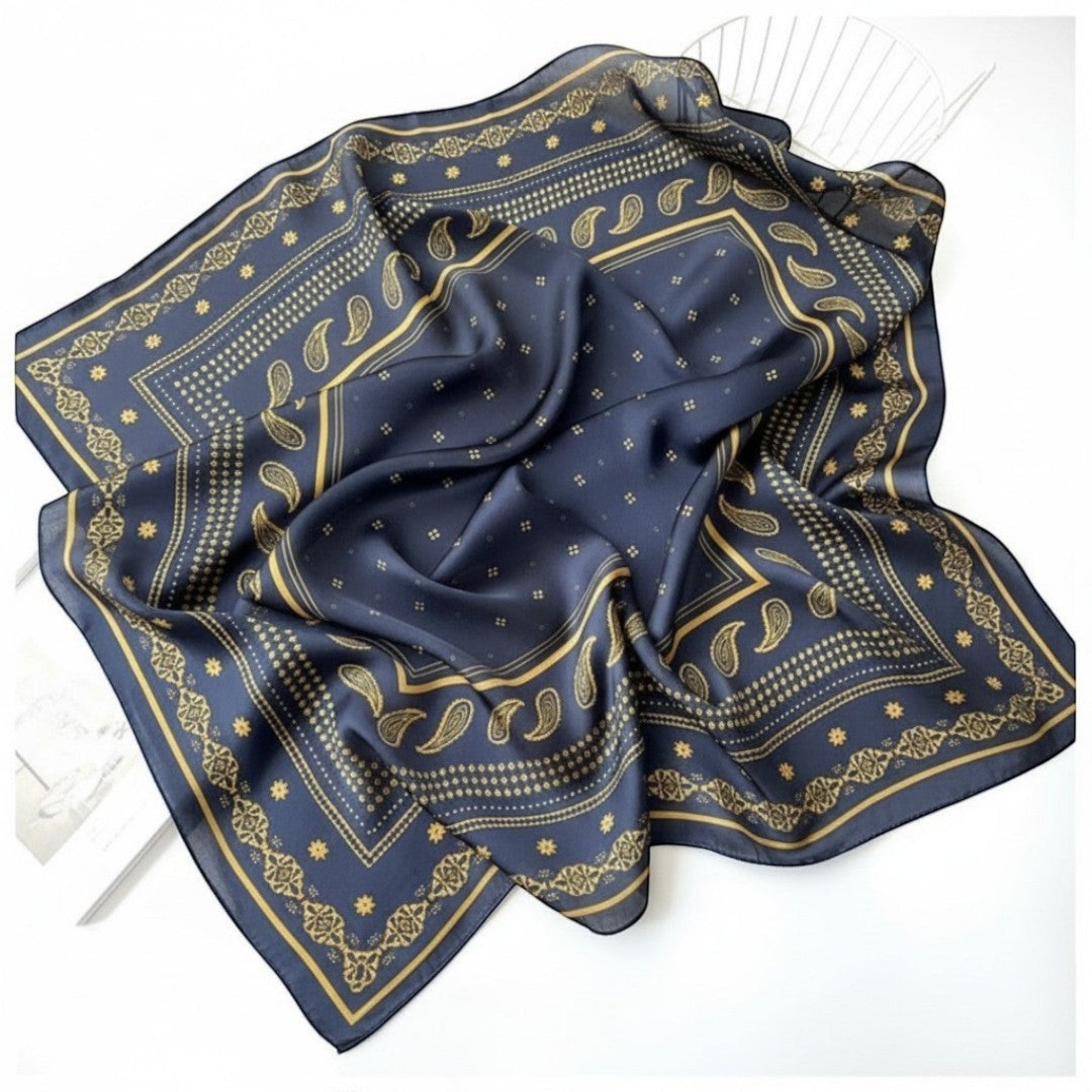 MiRA kvadratisk scarf i marinblått med ett sofistikerat geometriskt mönster i guldtoner, tillverkad i mjuk polyester.