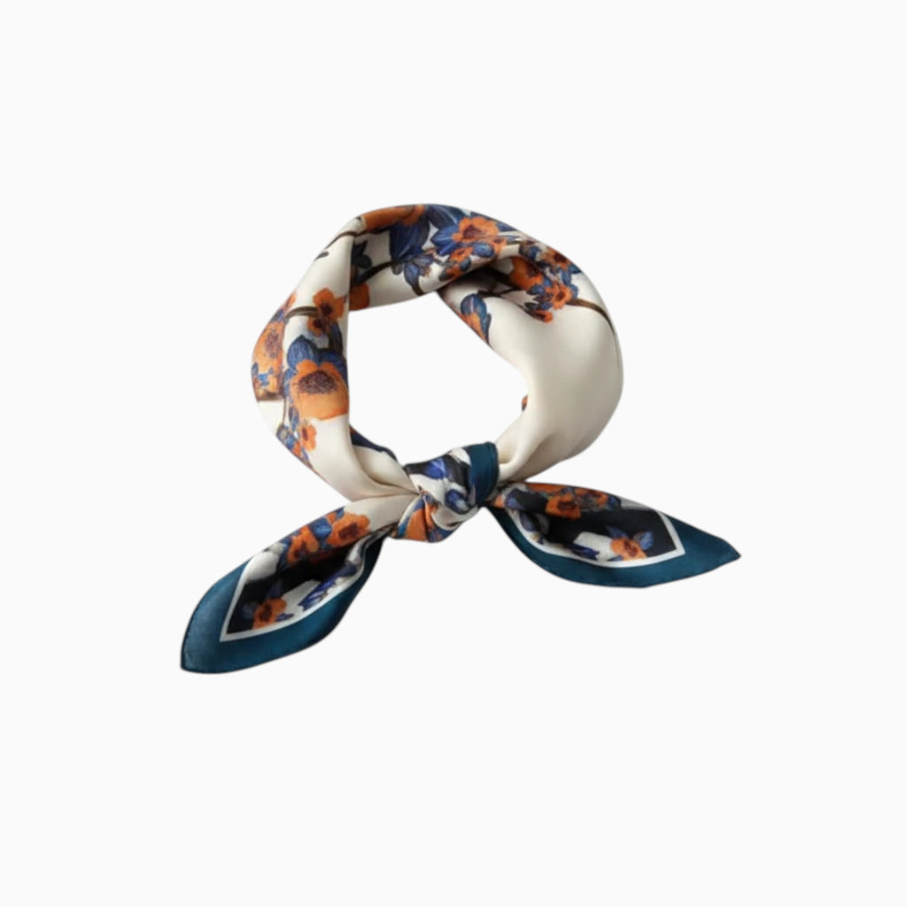 MiRA mönstrad scarf i polyester med blommotiv i orange, blått och vitt, knuten i en elegant rosett.