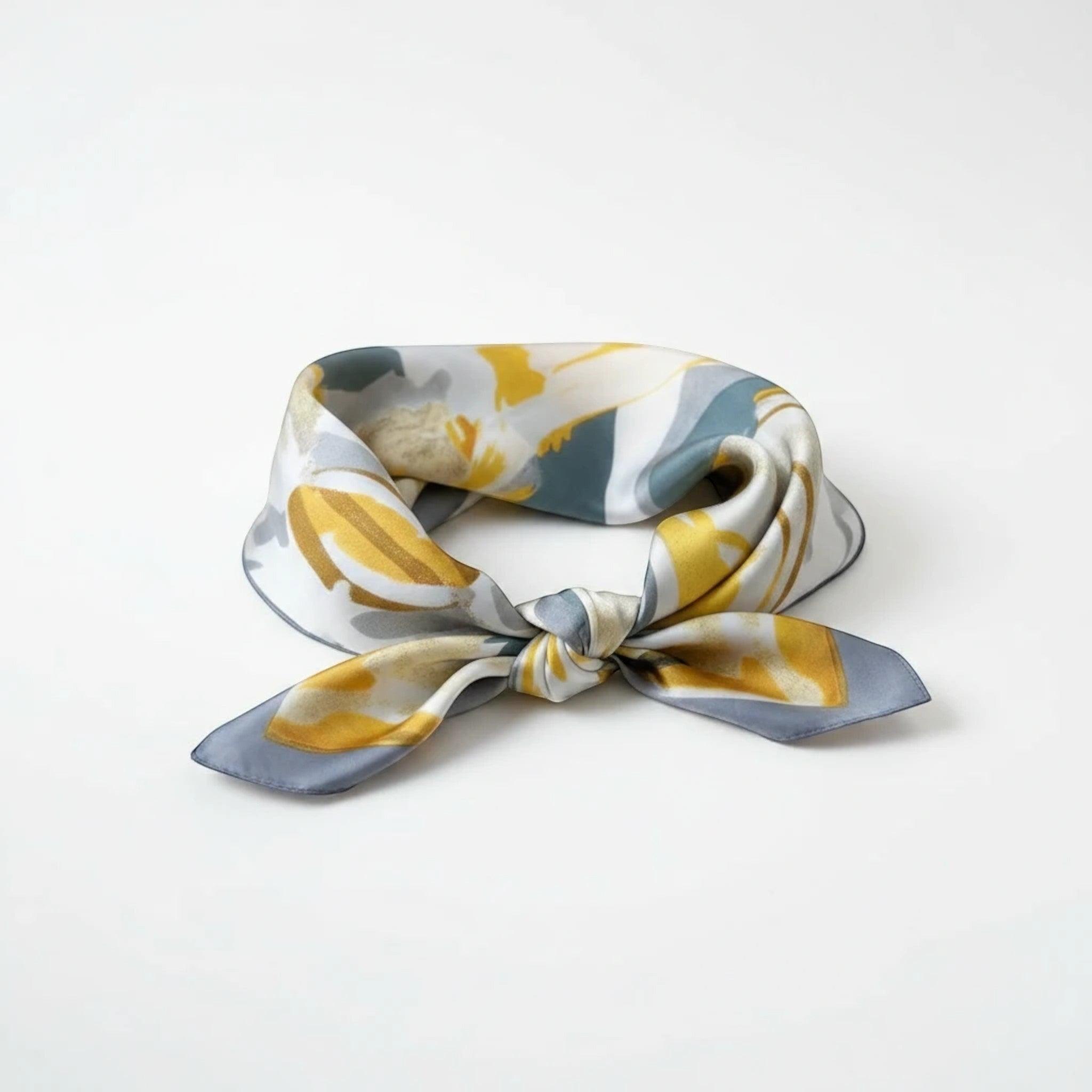MiRA mönstrad halsduk i siden med abstrakt motiv i grått och gult, knuten som en elegant accessoar.