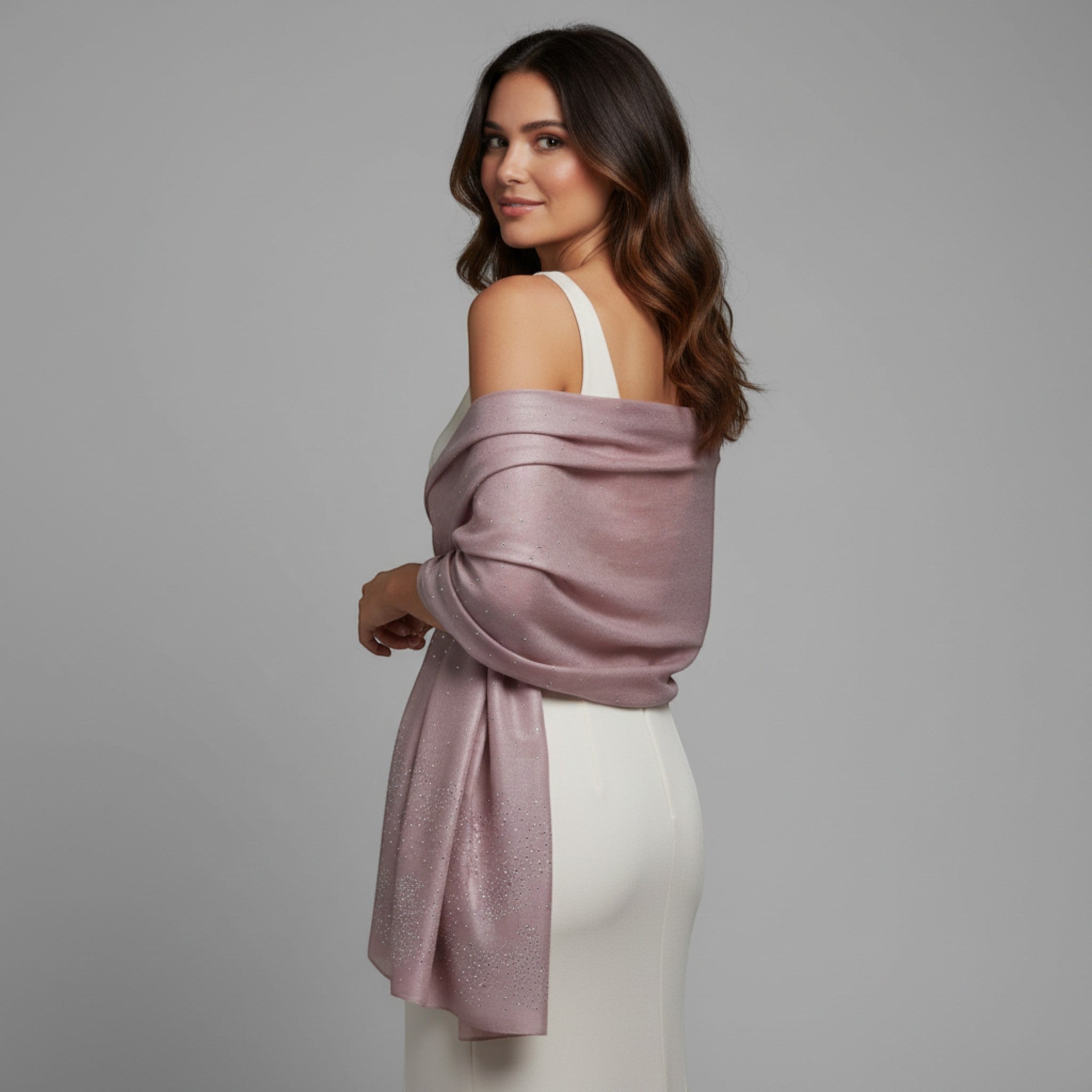 MiRA persikoröd glittrig sjal i polyester draperad över en vit festklänning på en kvinna med mörkt vågigt hår.