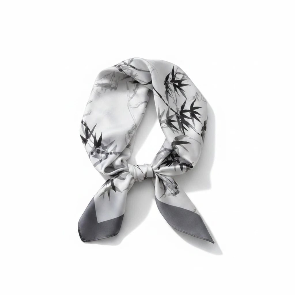 MiRA scarf i sidenliknande polyester med svartvitt bambumönster och elegant lyster, knuten i en klassisk stil.