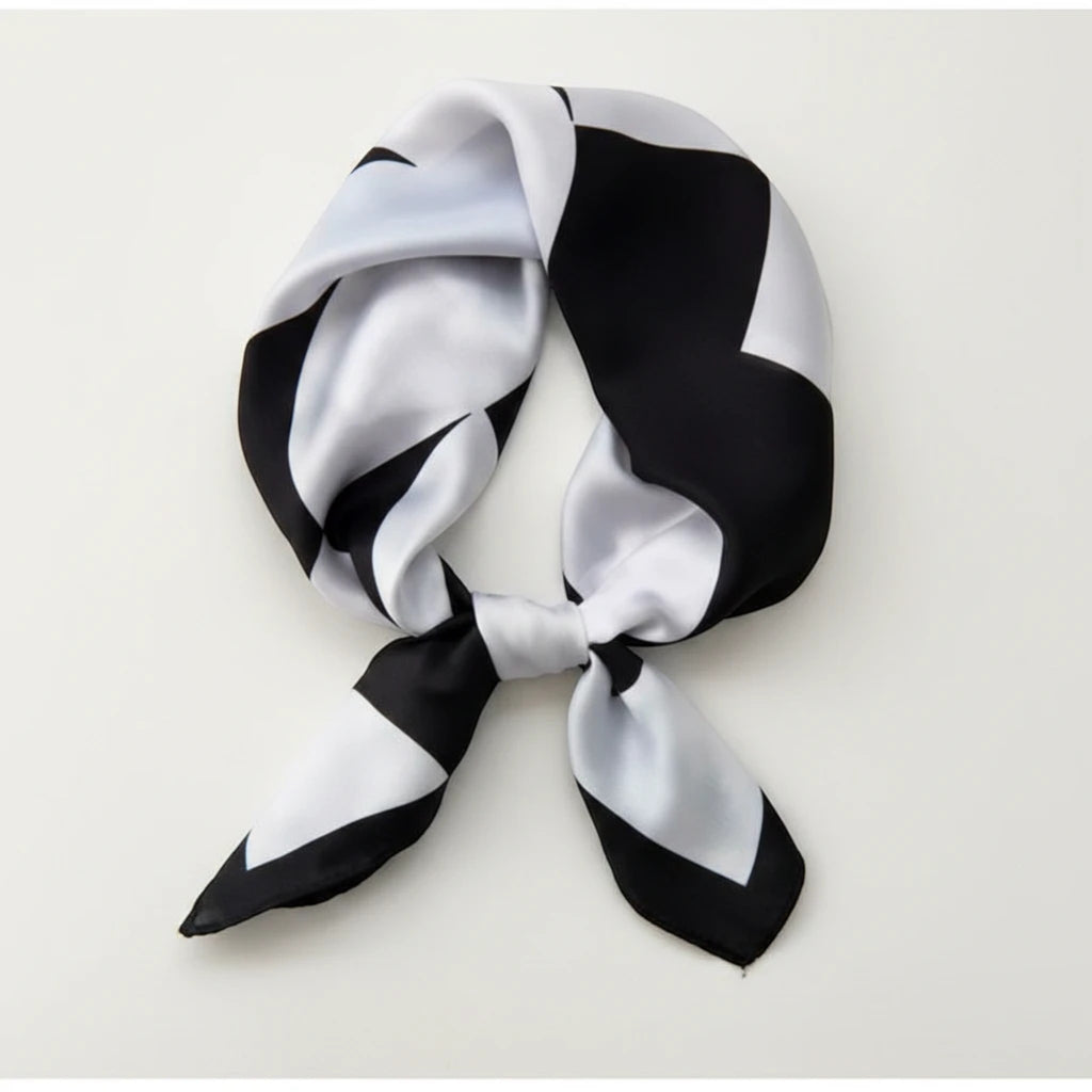 MiRA scarf i mjuk polyester med svartvitt geometriskt mönster, knuten i en elegant stil.