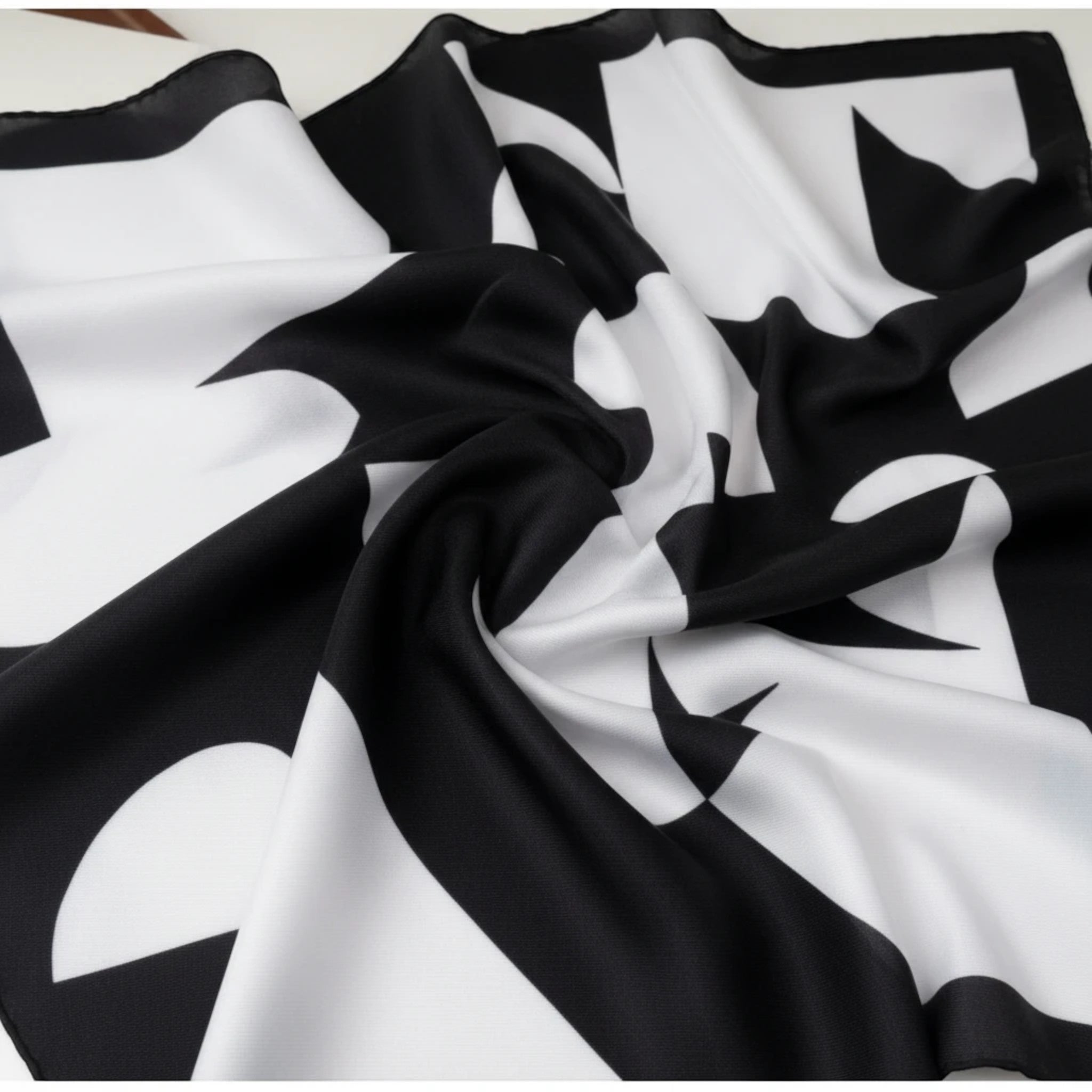 MiRA scarf i mjuk polyester med ett modernt svartvitt geometriskt mönster i en elegant och följsam design.